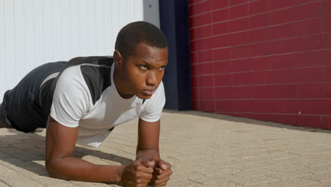 joven negro haciendo flexiones antes de correr al aire libre