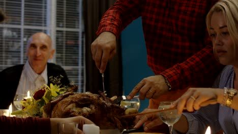 man carving turkey on thanksgiving dinner