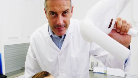 dentista ajustando la luz dental sobre una paciente femenina
