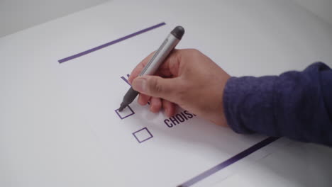 close up of anonymous male voter filling out paper ballot during elections close up of anonymous african american man making choice voting for presidential candidate or political party in voting booth male voter fills out paper ballot during elections civic duty concept