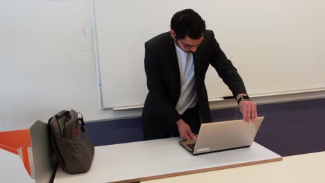 young male teacher prepares laptop for class