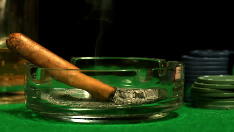 Cigar-smouldering-in-ashtray-on-casino-table