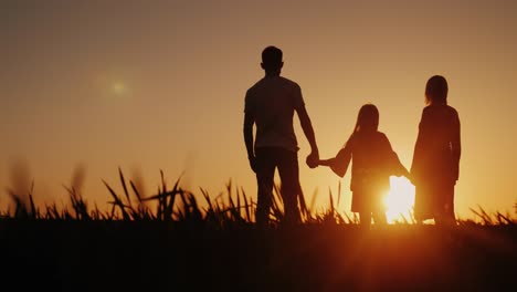 a happy family of three people meets the dawn in a picturesque place. holding hands