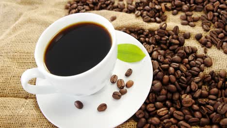 black coffee, coffee beans and leaf on sack