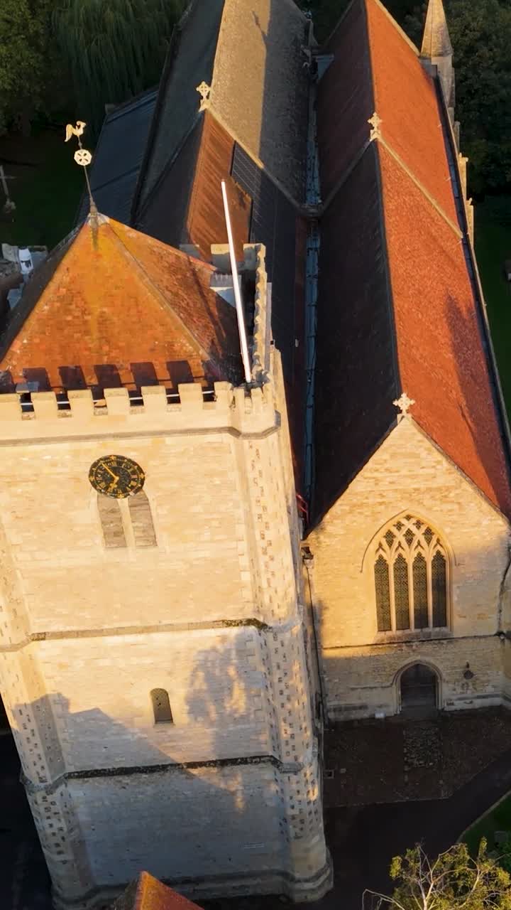 Vertical Aerial drone orbit of Dorchester Abbey in Oxfordshire, England. Starting right of the abbey frontage, it moves left while rising, casting evening shadowns, ends with top-down view of roof