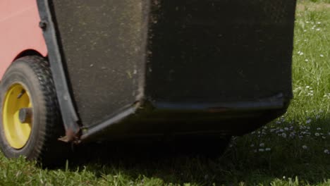 closeup riding landscaper lawn mower cutting grass during sunny daytime