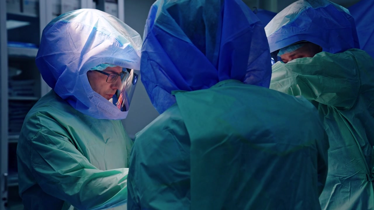 Squadra di chirurghi ortopedici che indossano caschi protettivi esegue un'operazione artroscopica. Collaborazione dei medici durante la procedura