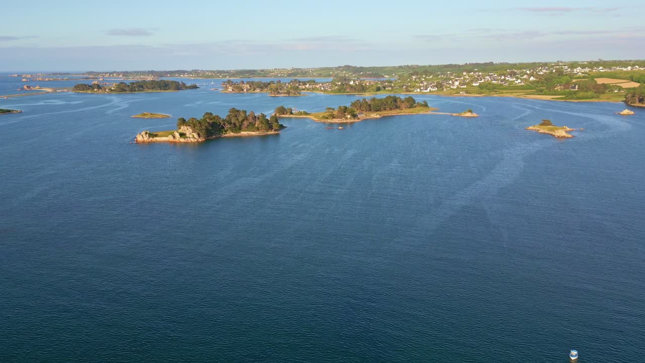 Distant drone view of islets and coastline stretching into the calm seawater at Port Blanc, Côtes-d'Armor, Brittany, France.
