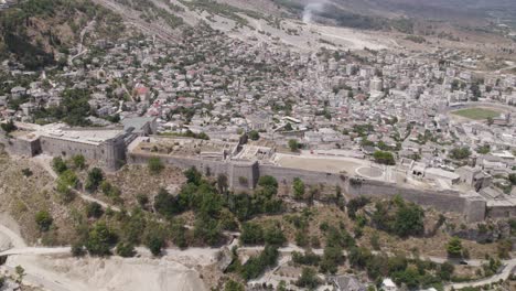 aerial orbiting view over gjirokaster castle historic albanian landmark with cityscape in background