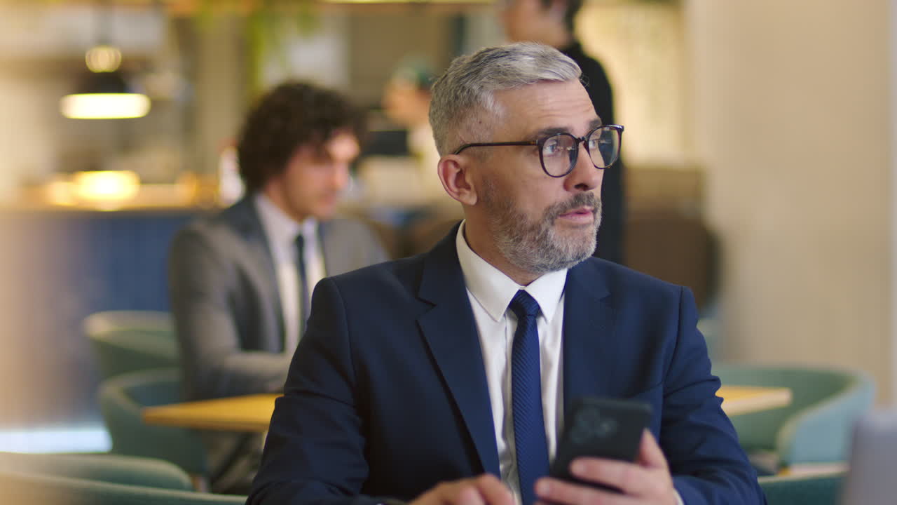 Uomo d'affari di mezza età che controlla lo smartphone in un bar