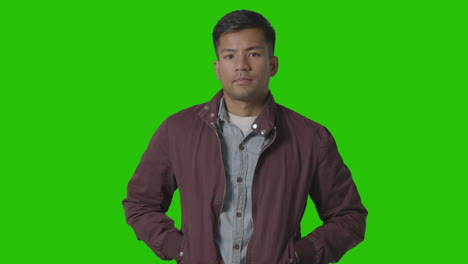 portrait of casually dressed serious young man against green screen