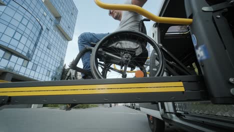 a man in a wheelchair on a lift of a vehicle for people with disabilities. lifting equipment for people with disabilities - man in wheelchair near the vehicle