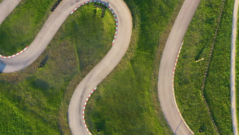 Toma-Aérea-De-Primer-Plano-De-Una-Sinuosa-Pista-De-Karting-Con-Luz-Solar-Dorada