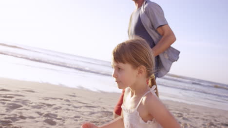 happy family playing on the beach at sunset on vacation