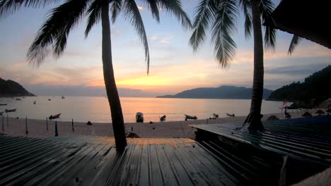 tourist filming a colourful sunrise time lapse from a hotel balcony with a beach view on the perhentian islands, malaysia. travel concept.