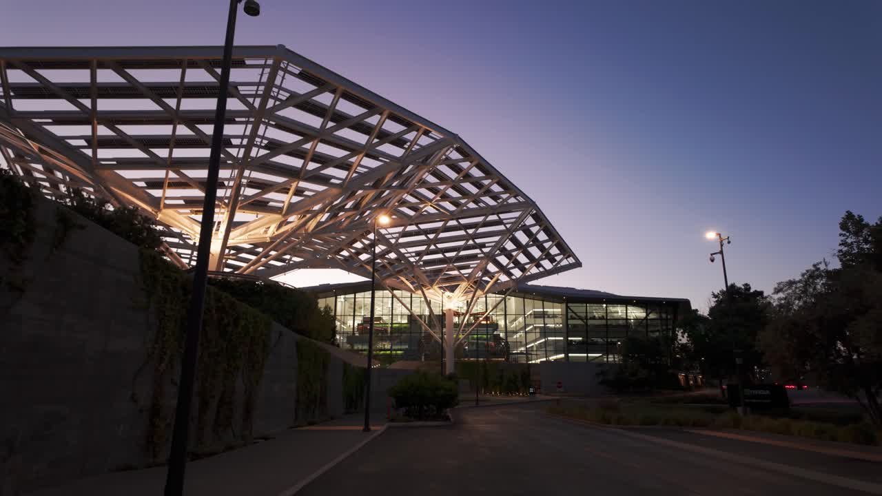 Gimbal wide panning shot of the solar tree canopy and the futuristic Voyager Building on the Nvidia campus at twilight in Silicon Valley, California. 4K