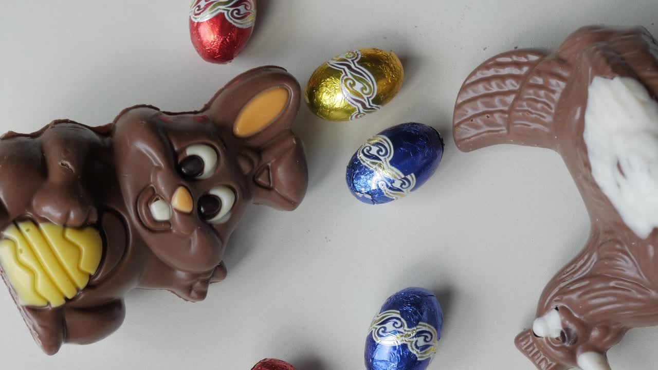 Coelho de chocolate e ovos de Páscoa em uma superfície branca, simbolizando alegria