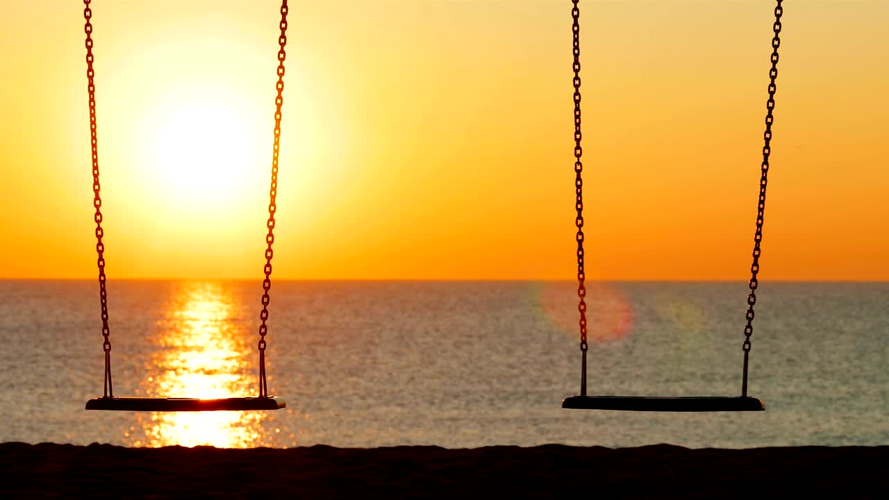 Altalena vuota al tramonto sulla spiaggia.