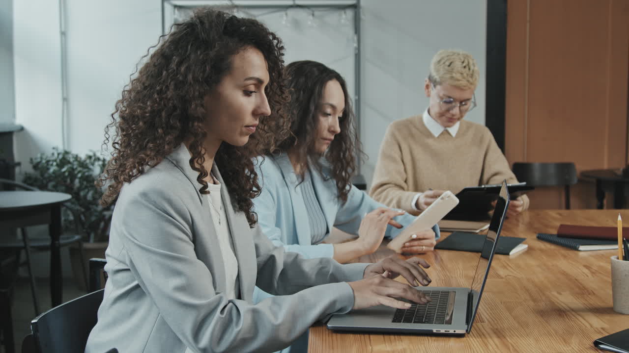 Side-View of Three Young Business Women Working at Conference Table