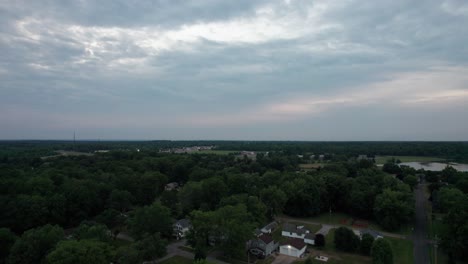 Eine-Panoramaaufnahme-Des-Sonnenuntergangs-über-Einer-Kleinen-Stadt,-Orangefarbene-Sonnenstrahlen-Beleuchten-Die-Häuser