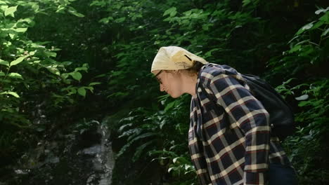 mujer caminando en un bosque exuberante junto a una cascada