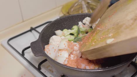 saltee las verduras picadas que van de la tabla de cortar de madera a la sartén de piedra y fríalas en aceite