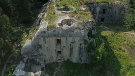 fast flying drone shot of an abandoned and overgrown bunker of world war one on a mountain, flying backward