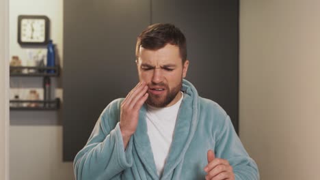 terrible facial expression of a young man with a swollen cheek from a sore tooth