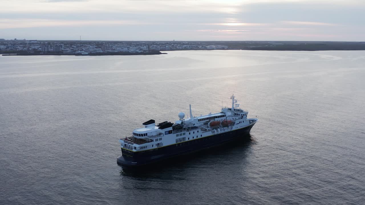 crucero de expedición anclado cerca de la costa de islandia durante la puesta de sol nublada, antena