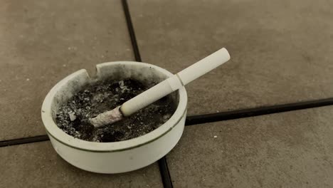 cigarette burning ash flick in ashtray close up