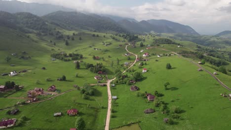 a lush village with a main road winding through hills and mountains, aerial view