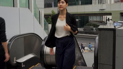 Japanese-business-woman-using-company-escalator-going-up.-Asian-female-worker.