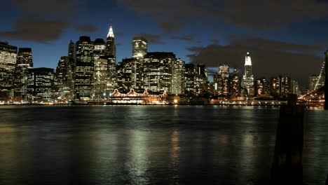 Slow-pan-of-an-accelerated-shot-of-clouds-in-shades-of-pink-and-purple-passing-over-the-New-York-City-skyline-from-golden-hour-to-night