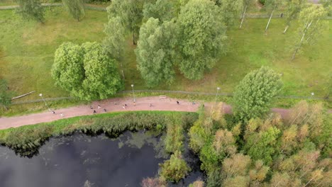 young people running fast in a park near water, aerial tracking