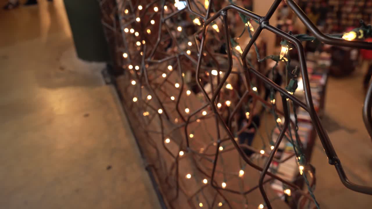 Vintage railings with lights on second floor of bookstore. People are blurred out in the backgroud. Books for sale.