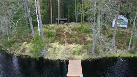 Hiker-and-Dog-at-Wind-Shelter-Cabin-in-Thick-Forest,-Aerial-Backward