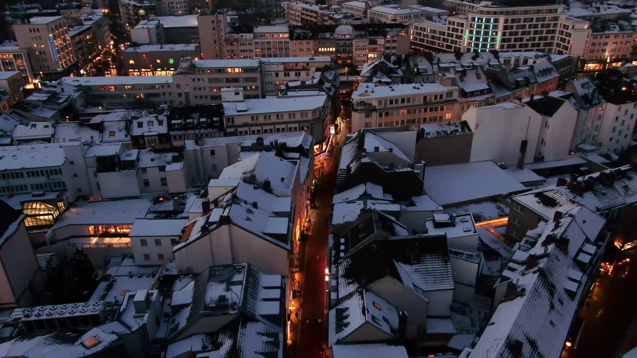 Aerial shot of Bonn city at night in winter. Snow covered city  at night. city lights at night, German city covered in snow, night drone shot of city at night covered in snow.