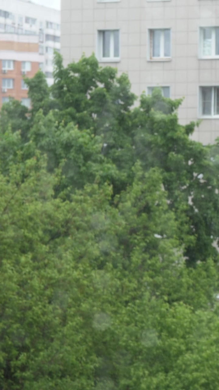 Janela com gotas de chuva e vista para o prédio de apartamentos