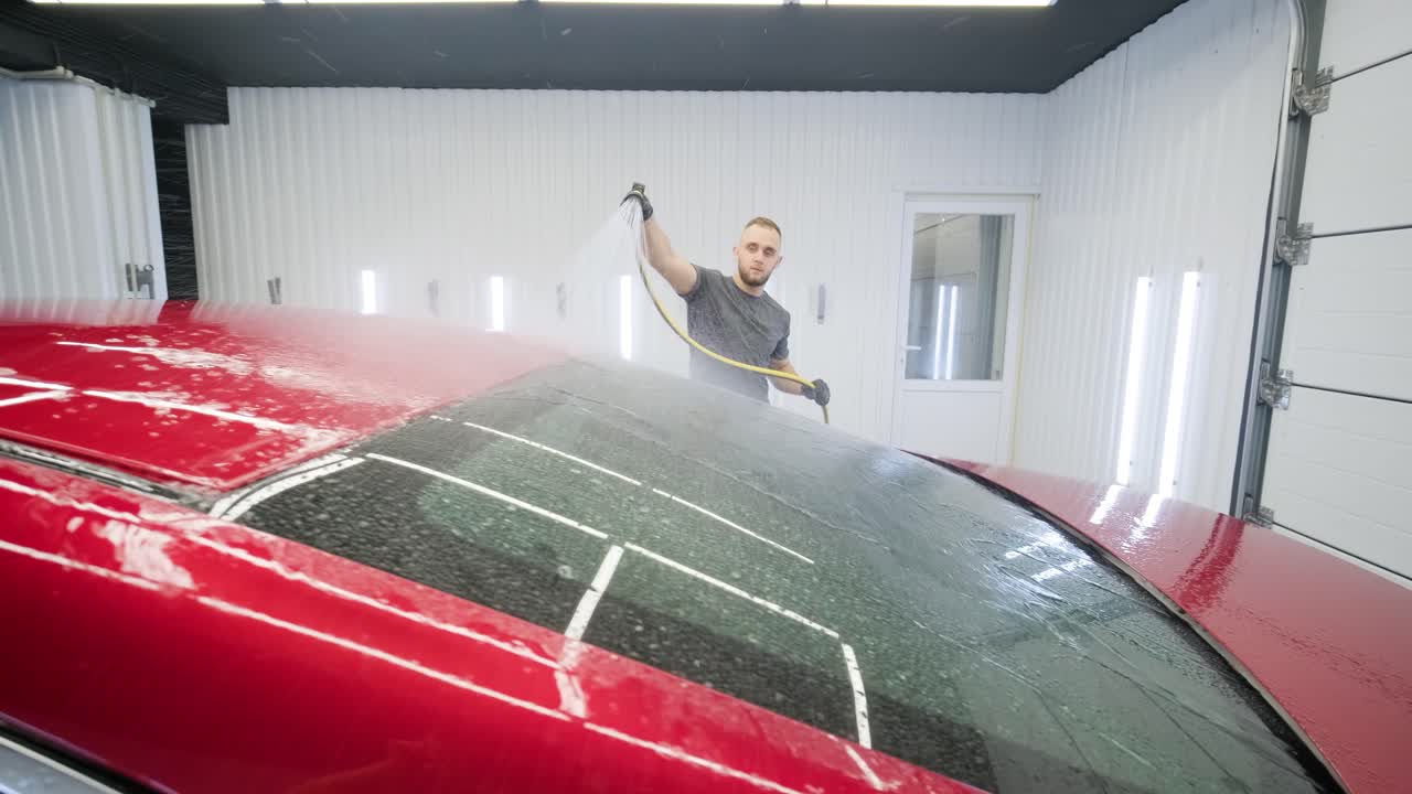 남자 노동자가 세탁장에서 빨간 차를 고 있다.