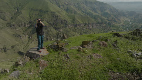 portrait of nature photographer standing on rocky mountain, taking photos of beautiful scenery in georgia