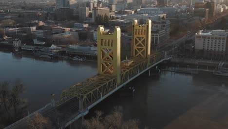 Aerial-drone-tilt-down-of-Tower-Bridge-and-Downtown-Sacramento,-CA,-including-Old-Sacramento---State-Capitol-in-background-during-sunrise