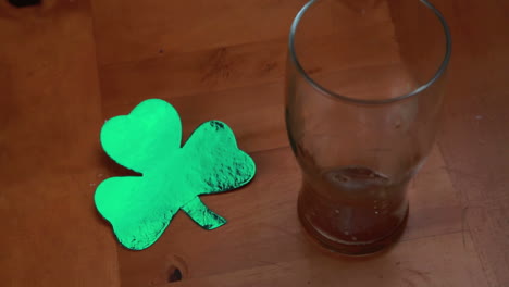 hand putting down empty pint beside large shamrock