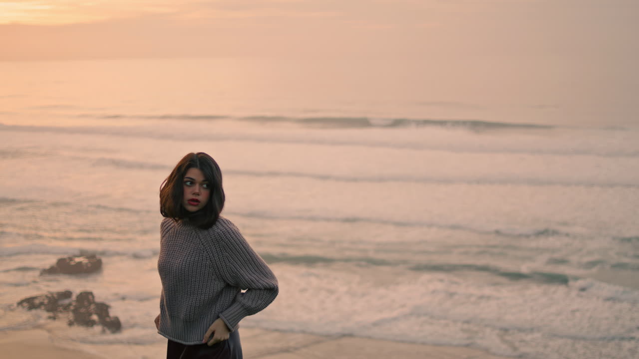 Ragazza che si gode un paesaggio marino nuvoloso in piedi vicino alle onde dell'oceano. Donna in piedi sulla riva del mare.