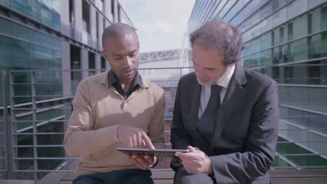 confident businessmen talking and using smartphones in city