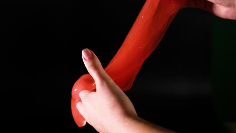 hands manipulating stretchy red slime