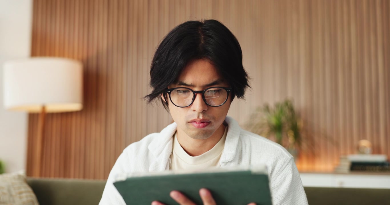 モダンなリビングルームでデジタルタブレットを使う若い男性
