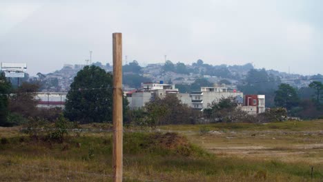 street view through barbed wire fence showcasing zone 18 favelas guatemala city, endless stacked houses, cultural architecture - slow-mo