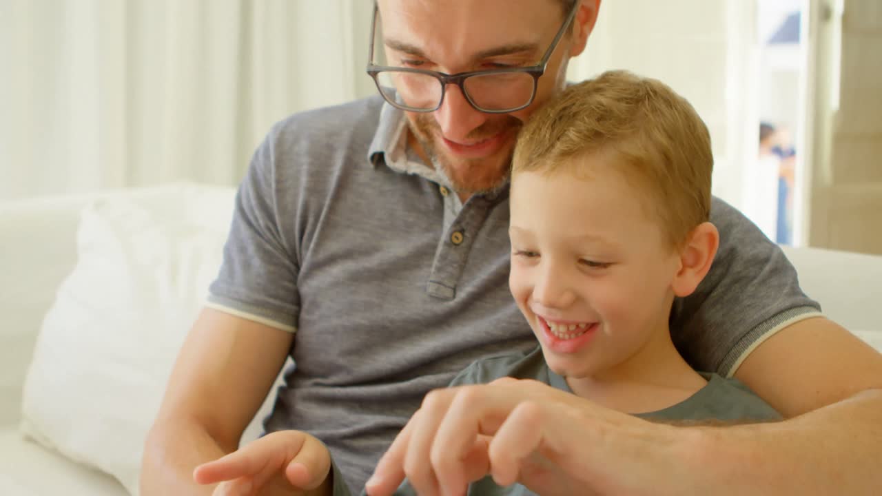 padre e hijo usando tableta digital en el sofá en casa 4k