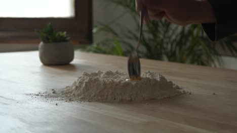 person preparing mix blending flour and egg yolk on wooden kitchen table surface making fresh pasta dough