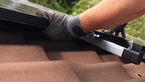 mounting solar panels on metal railings on tile roof, closeup on hands